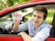 Junger Mann im Auto zeigt Führerschein